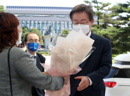 이재명 더불어민주당 의원이 7일 오전 서울 여의도 국회 의원회관에 첫출근하며 지지자로부터 꽃다발을 받고 있다.<국회사진기자단·연합뉴스>